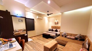 A hotel room with a bed, a sofa, a desk with a chair, and a mirror. - Hotel Urban Galaxy (Amritsar)