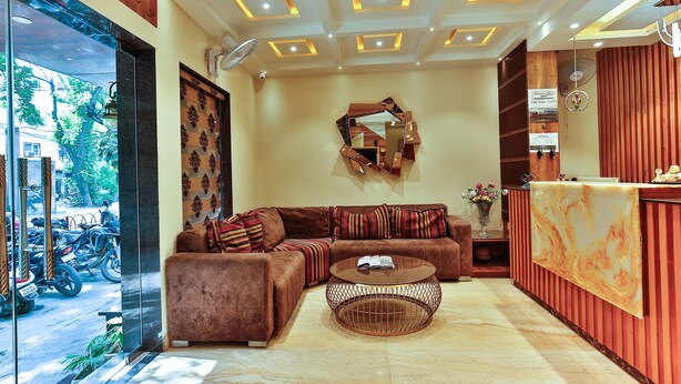 A modern hotel lobby with a sofa, a round coffee table, and a reception desk. - Hotel Urban Galaxy (Amritsar)