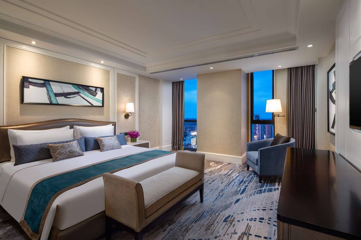 Une chambre d’hôtel avec un grand lit, un canapé, un bureau et une vue sur la ville.