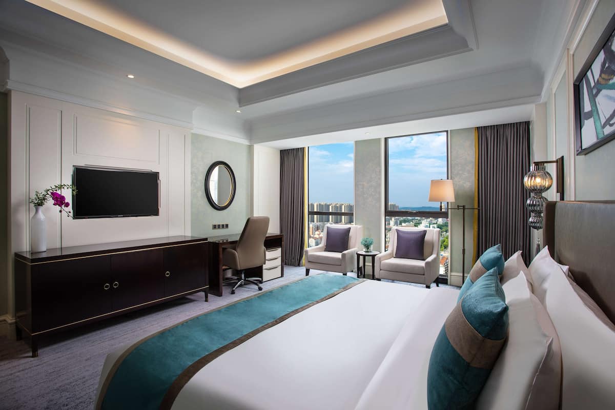 Une chambre d’hôtel avec un grand lit, un bureau, une télévision, une vue sur la ville et un balcon.