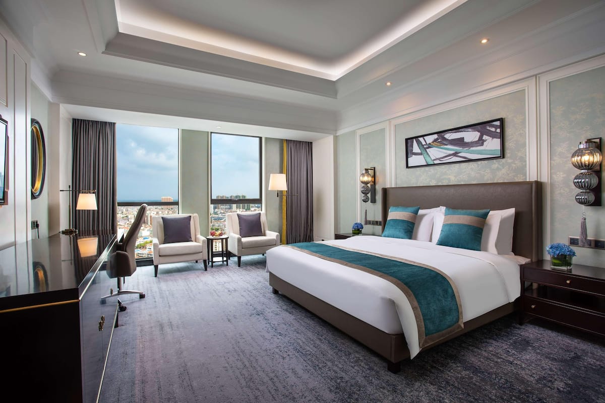 Amplia habitación de hotel con una cama grande, un escritorio, una silla y vistas a la ciudad.