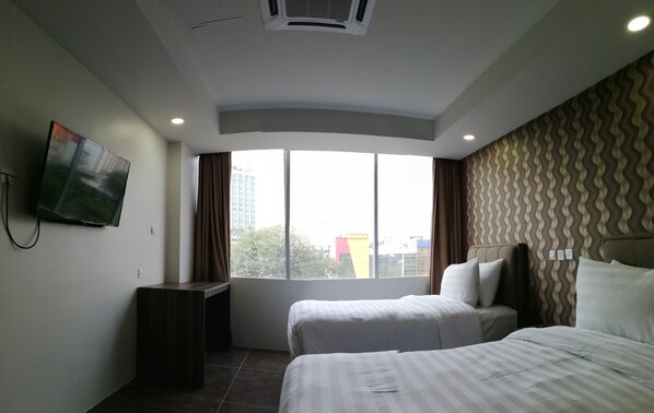 A hotel room with two beds, a TV mounted on the wall, a large window, and a patterned wall.