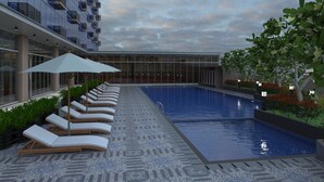 Zona de piscina moderna amb gandules i ombrelles, emmarcada per un edifici amb grans finestres i un paviment de rajoles.