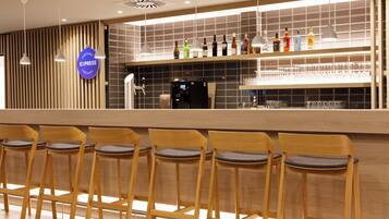 A bar area with a coffee machine, shelves of bottles, and bar stools.