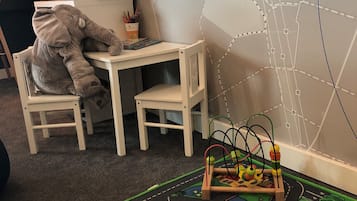 Ein Kinderspielbereich mit Spielzeug-Elefant, Schreibtisch und einer bunten Spieldecke.