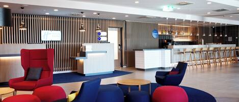 Un hall d'hotel modern amb taulell de recepció, zona de seients i bar.