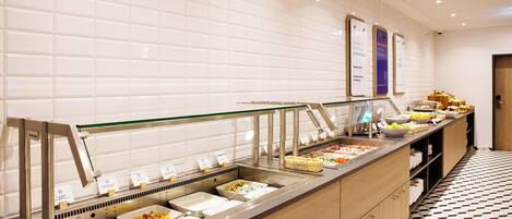A buffet area with various food options, a tiled wall, and a patterned floor.