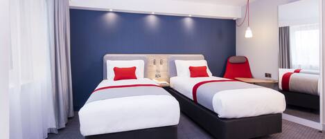 Et hotelværelse med to senge, et skrivebord og et spejl.