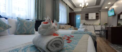 A hotel room with a neatly made bed, a dining area, and a TV mounted on the wall.