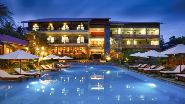 A hotel with a swimming pool, lounge chairs, umbrellas, and a well-lit exterior. - Azura Resort Phu Quoc (Phu Quoc)