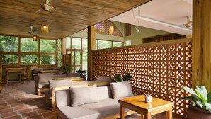 A wooden interior with a sofa, table, and chairs, a lattice partition, and large windows. - Azura Resort Phu Quoc (Phu Quoc)