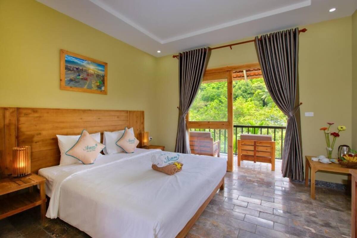 A hotel room with a large bed, wooden headboard, and a balcony with curtains.