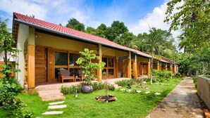 A bungalow-style hotel with a red-tiled roof, a covered porch, and a well-maintained garden with a stone pathway. - Azura Resort Phu Quoc (Phu Quoc)