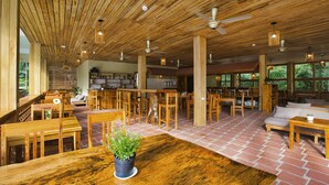 A spacious restaurant with wooden furniture, a brick floor, and large windows offering a view of the outdoors. - Azura Resort Phu Quoc (Phu Quoc)