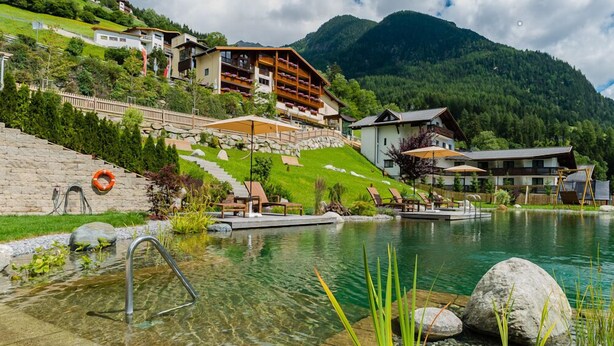 A mountain resort with a clear pool, outdoor seating, and a view of the surrounding hills. - Jerzner Hof (Jerzens)