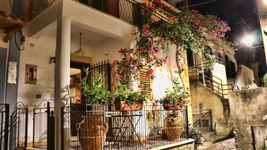 A building with a balcony, potted plants, and a staircase.