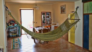 A hammock in a room with a dining area, a cabinet, and a door leading outside.
