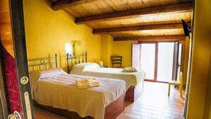 A room with two beds, wooden beams on the ceiling, and a large window.