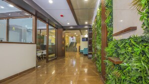 A hallway with glass doors, a staircase, and a green wall with plants. - Mango Suites Viera (Hyderabad)