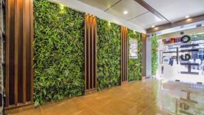 A lobby with a green wall, polished floor, and a visible store with a sign. - Mango Suites Viera (Hyderabad)