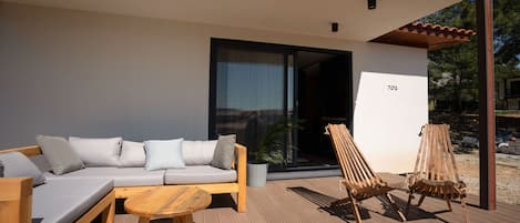 A wooden deck with a sofa, a table, and two wooden chairs.