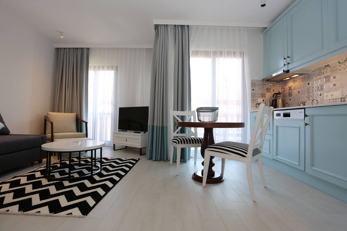 A modern living room with a sofa, coffee table, TV, and dining area with chairs and a table.