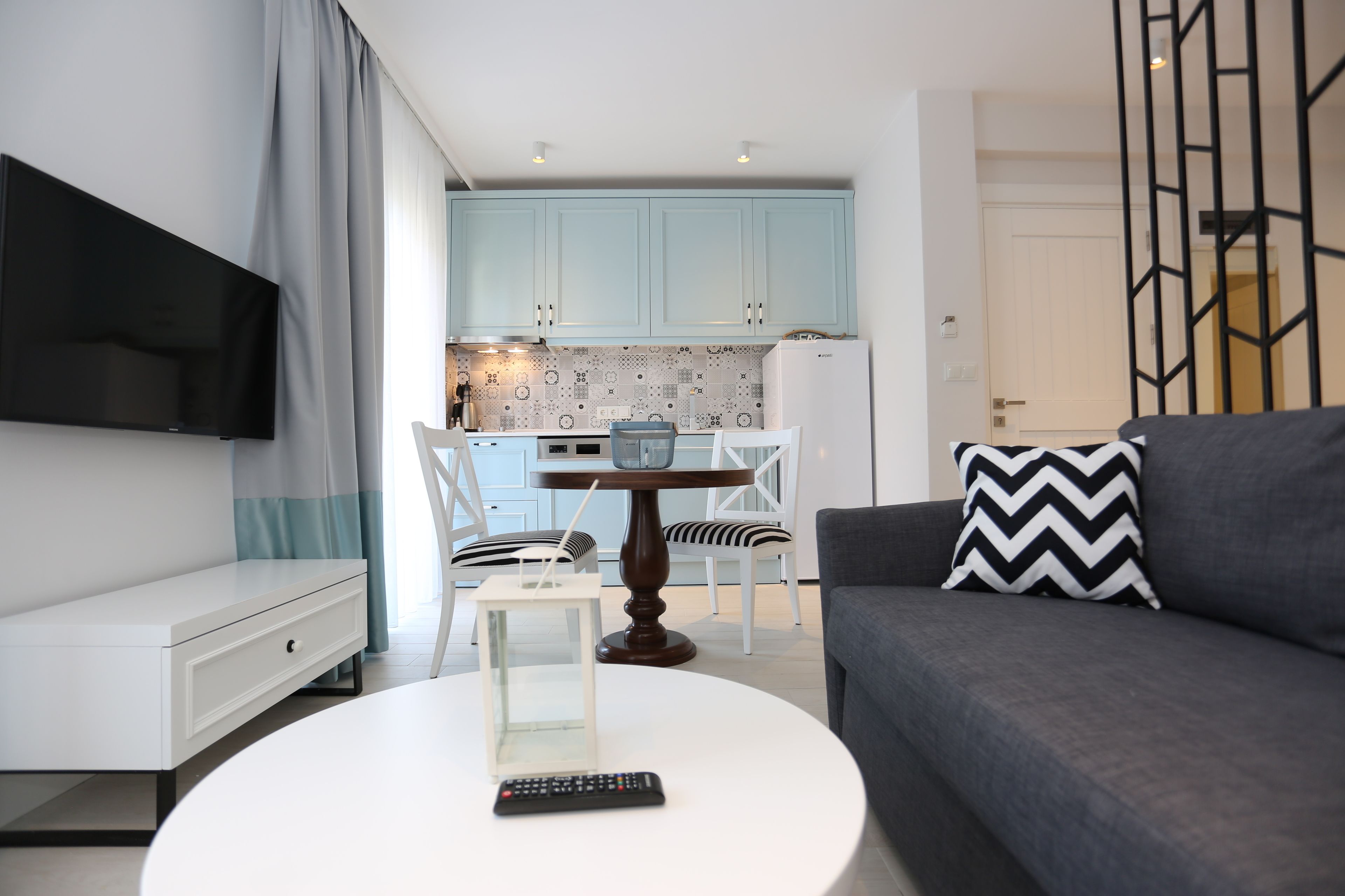 Un salón moderno con un sofá gris, una mesa de centro blanca y un televisor montado en la pared.
