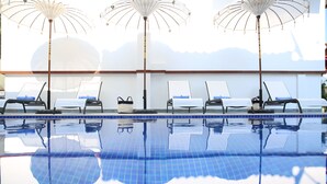 Une piscine avec des chaises longues et des parasols.