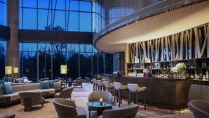 A modern bar area with a curved counter, seating with round tables, and a large window offering a view of the outdoors. - Hangzhou Marriott Hotel Lin'an (Hangzhou)