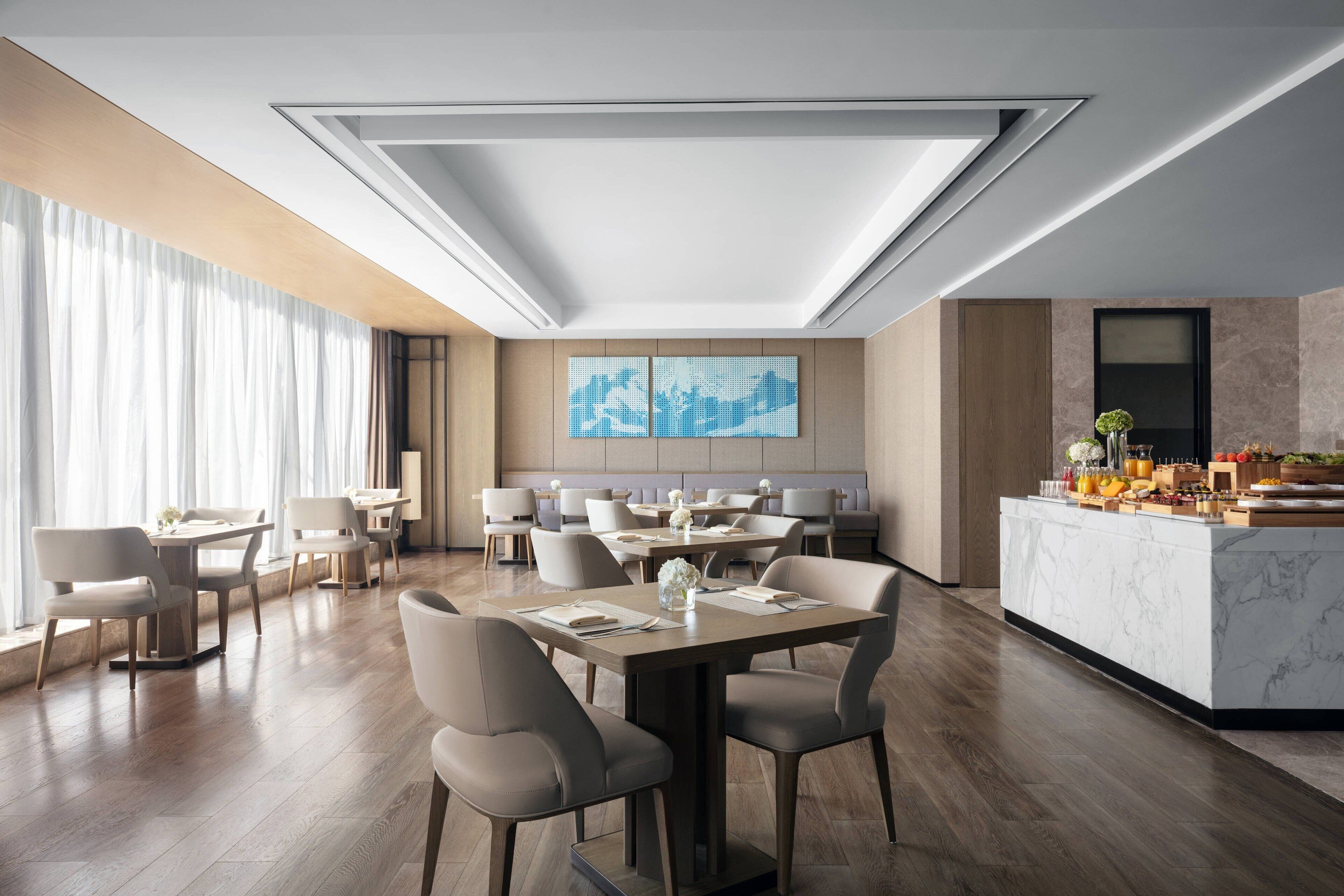 A modern dining area with a marble bar, wooden flooring, and contemporary furniture.