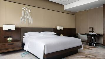 A modern hotel room with a large bed, bedside tables, a desk, and a chair.