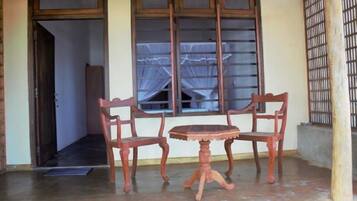 A room with a wooden door, a window with a curtain, and a small round table with two chairs.