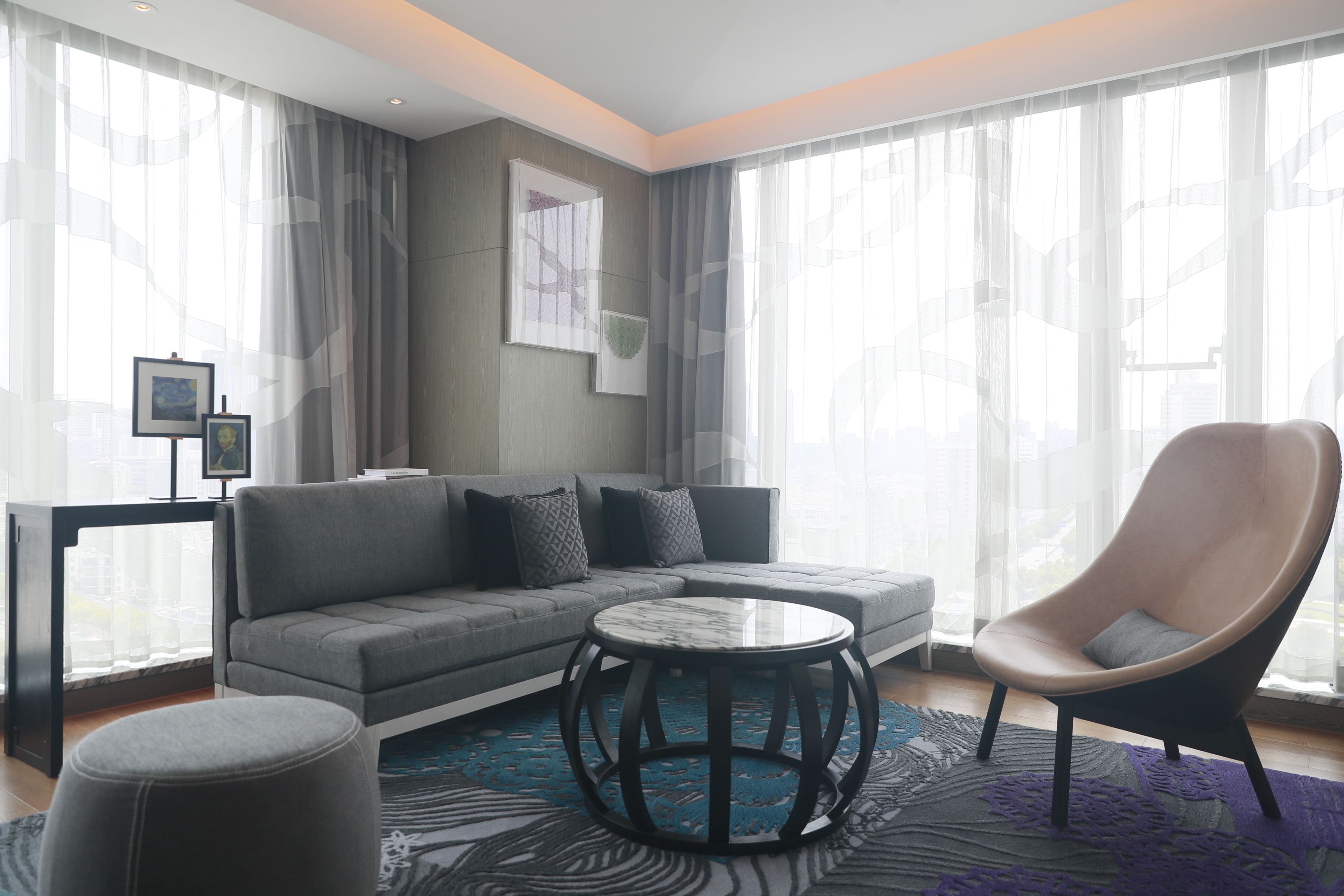 A modern living room with a grey sofa, a round coffee table, and a black armchair.