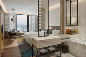 A modern hotel room with a large bed, a sitting area with a laptop, a bathroom with a large mirror and a bathtub, and a city view. - Renaissance Hangzhou Northeast Hotel (Hangzhou)