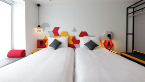 A double bed with white linens, a red and yellow geometric wall decoration, and a red and black nightstand with a lamp. - ibis Styles Tokyo Bay (Urayasu)