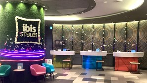 A modern interior with a reception desk, check-in counters, and colorful seating. - ibis Styles Tokyo Bay (Urayasu)
