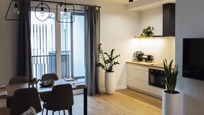 Cozinha moderna com área de refeições, piso de madeira e uma grande planta em vaso.