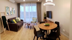 Uma sala de estar moderna com um sofá marrom, uma mesa de jantar de madeira e uma televisão na parede.