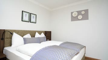 A neatly made bed with a patterned bedspread, a wooden headboard, and two framed pictures on the wall.