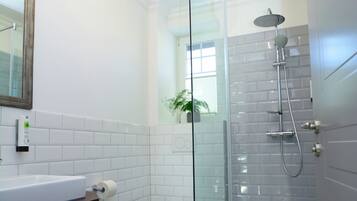 Ein modernes Badezimmer mit Duschkabine aus Glas, einem weißen Waschbecken und Fliesen mit Muster.