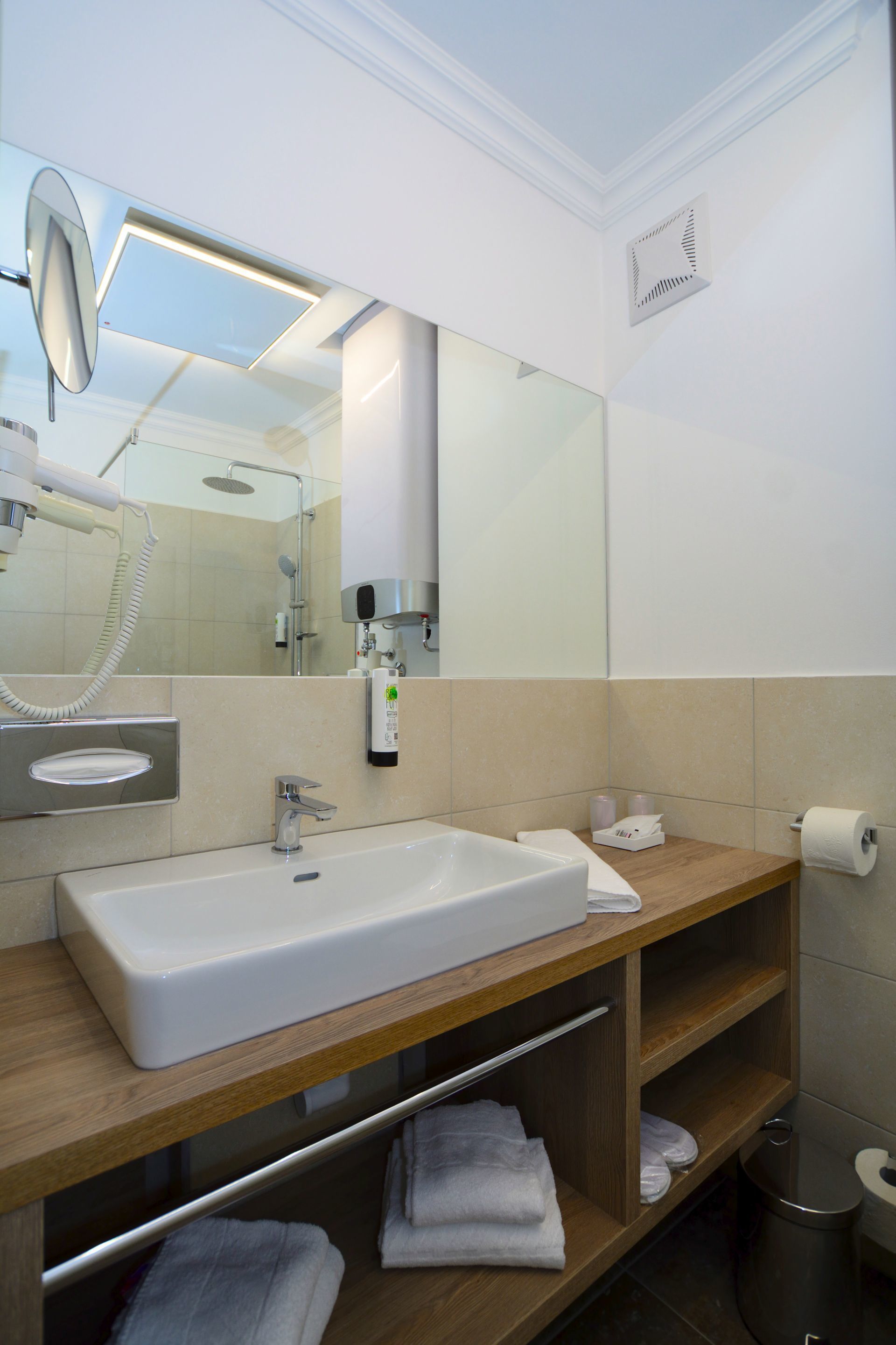 A modern bathroom with a large sink, mirror, and towel rack.