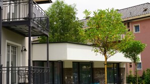 A modern two-story building with a balcony, a small tree, and a well-maintained lawn. - Apart of me Villach (Villach)