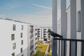 A bird perched on a balcony railing overlooking a modern apartment building with multiple balconies and a central courtyard. - Sweet Apartments- Ericius Group (Poznan)