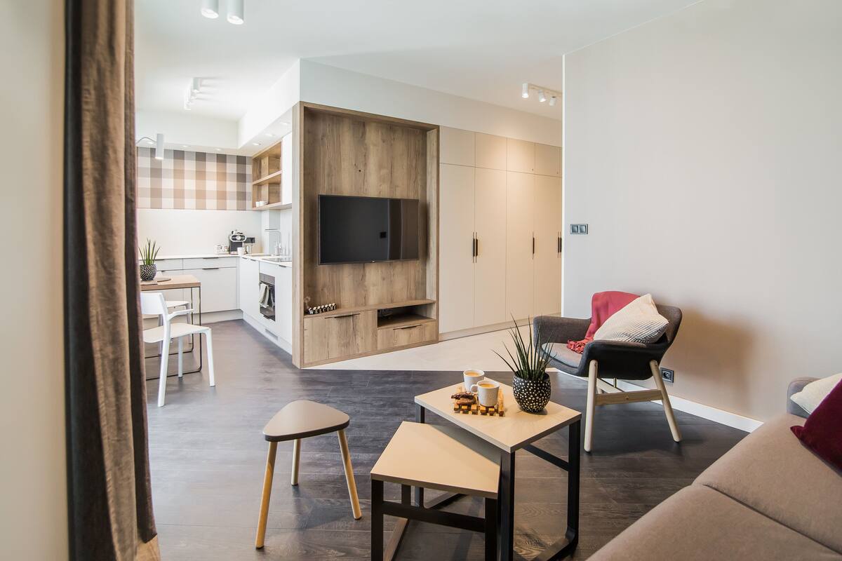 A modern living room with a sofa, a coffee table, and a TV mounted on a wooden wall.