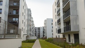 Un moderno edificio condominiale con balconi, un vialetto lastricato e un prato curato.