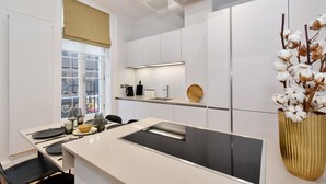 A modern kitchen with white cabinetry, a built-in stove, and a window with a view of the city. - Light-Filled, Contemporary Retreat near The Ritz (London)