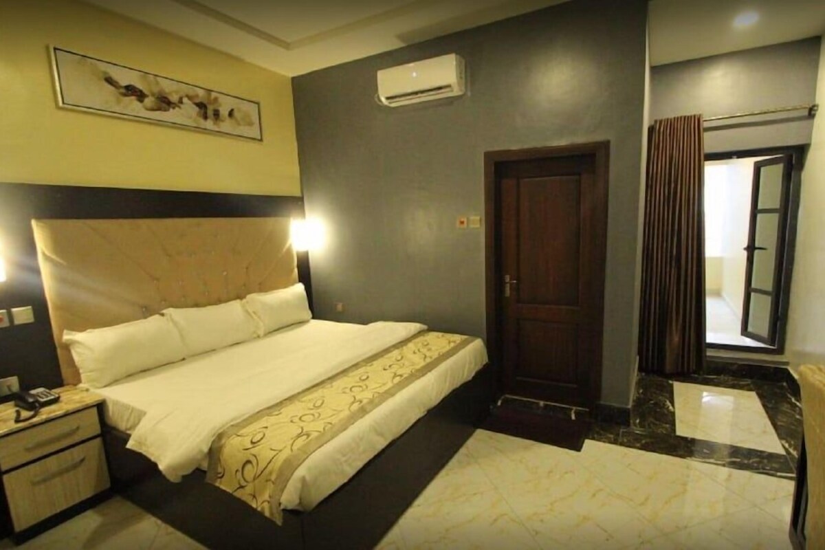 Quarto de hotel com uma cama grande, mesa de cabeceira e espelho.