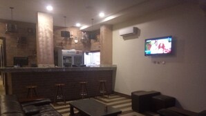 A living room with a bar area, leather sofas, and a flat-screen TV mounted on the wall. - De Gladys Hotel (Enugu)
