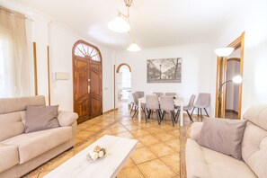 A living room with two sofas, a coffee table, and a dining area with chairs and a table.