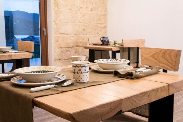 A wooden dining table with ceramic bowls, plates, and a spoon.